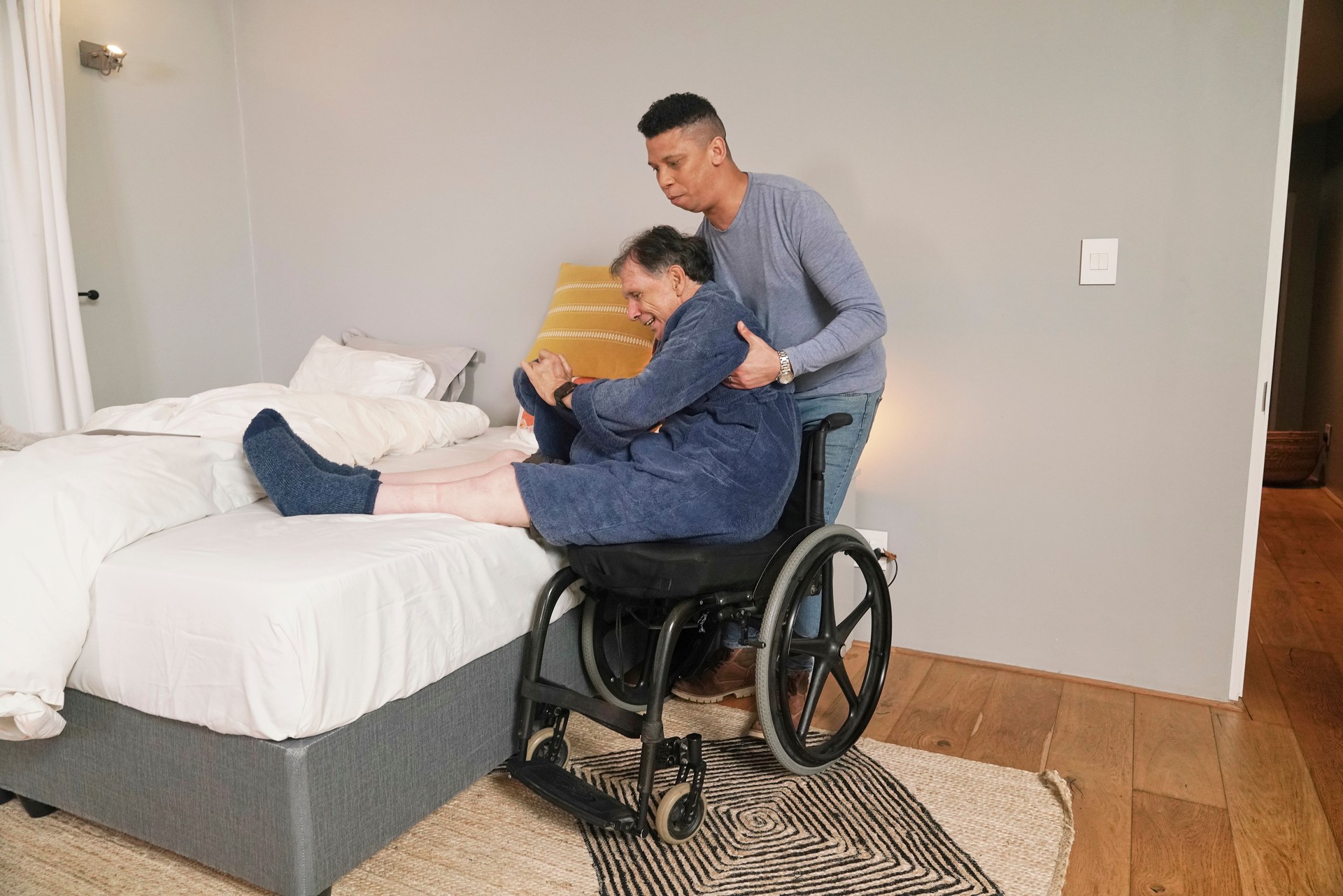 Man helping disabled friend getting out of bed
