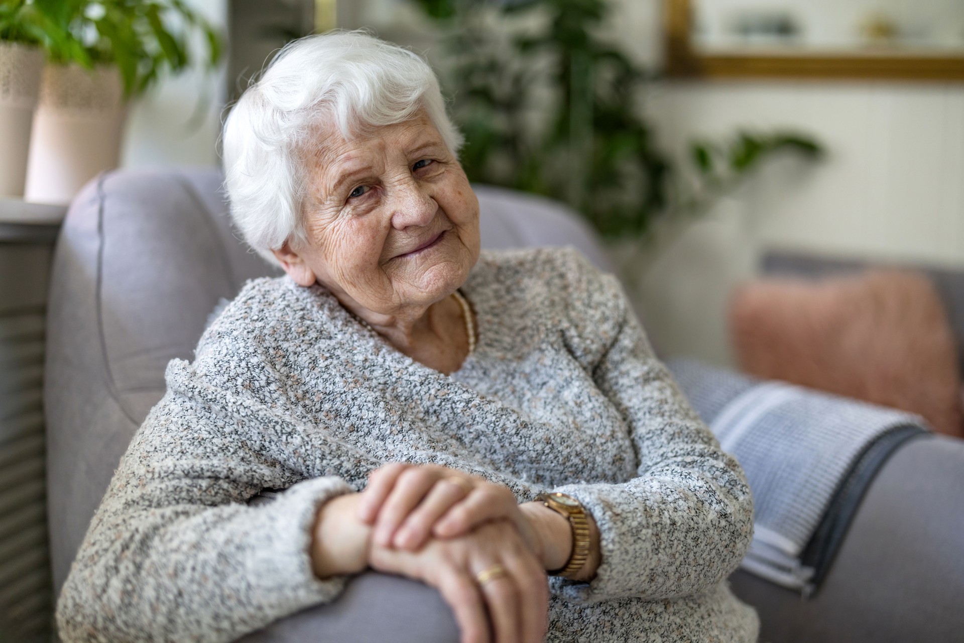 Elderly woman at her home sitting in armchair and looking at camera
